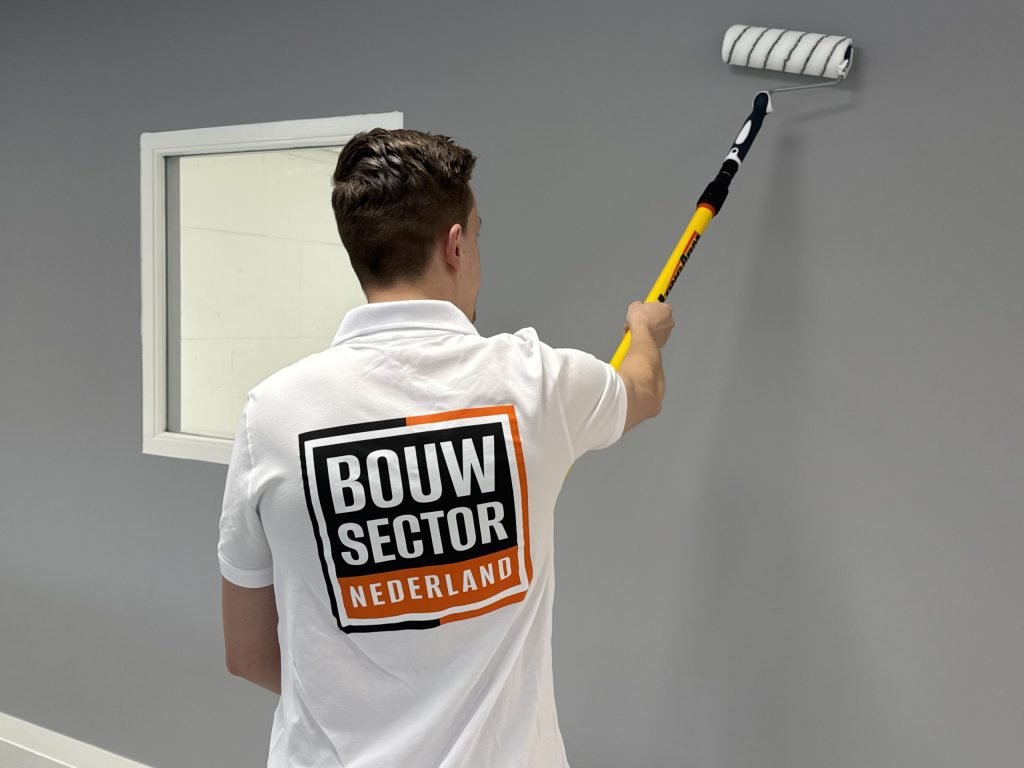 Schilder zet een grijze laag bovenaan de muur naast een wit binnenraam